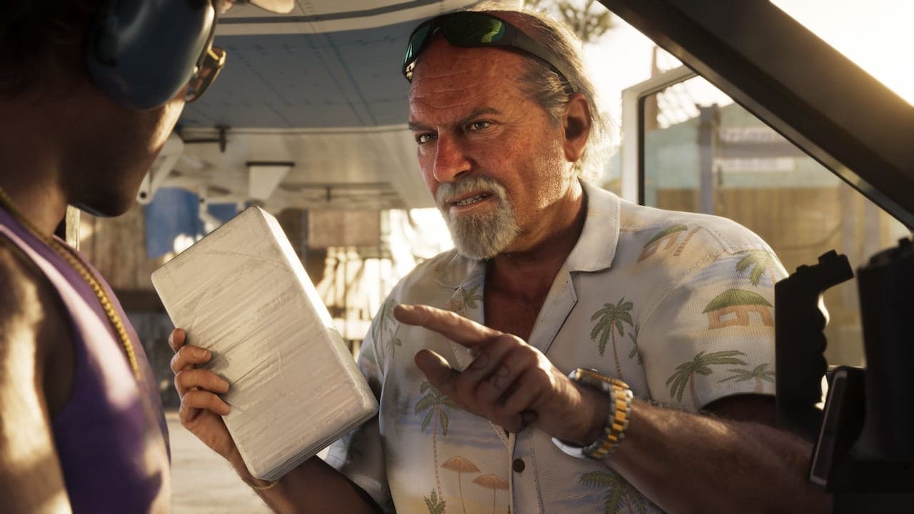 Brian in a palm-print shirt gesturing at a wrapped package held out to him inside a boat shed at sunset.