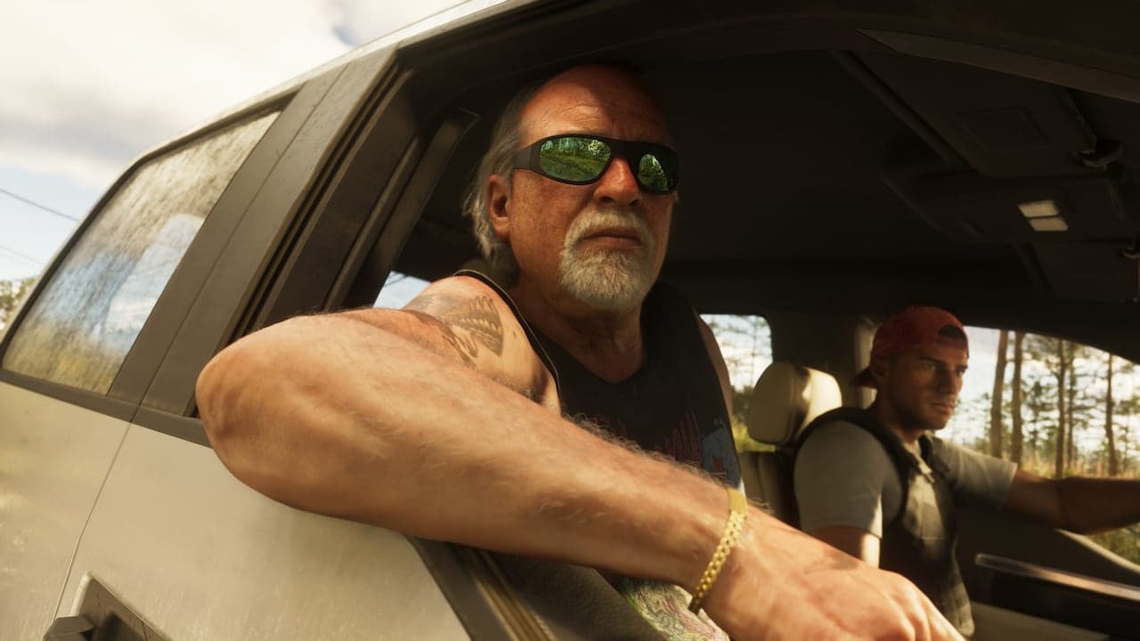 Brian leaning out of the passenger window of a pickup truck on a wooded road, a younger man driving.