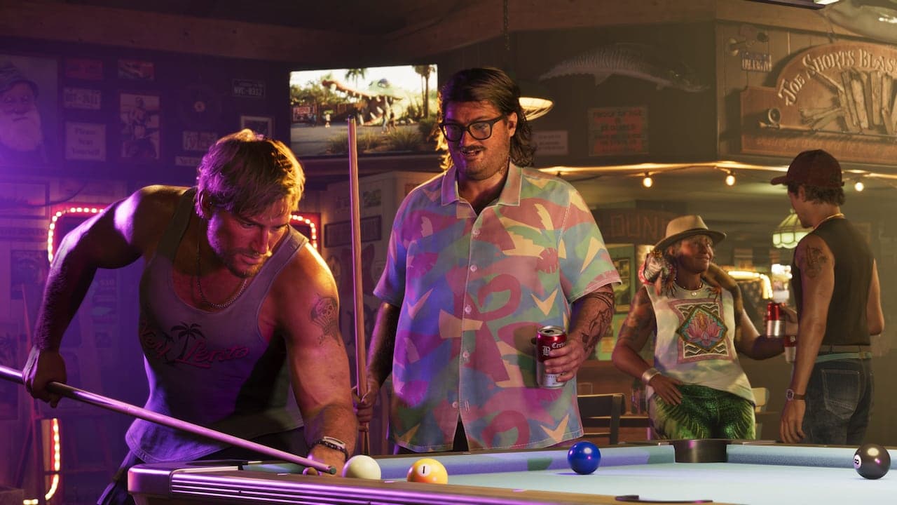 Cal watching a game of pool in a dive bar, a can in his hand, in glasses and a pastel patterned shirt.