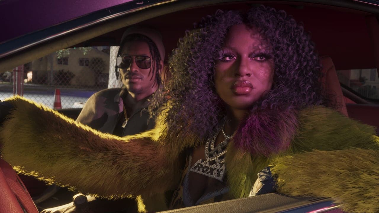 One of Real Dimez in the passenger seat of a car in a fur coat and a nameplate chain, a man in sunglasses in the seat behind.