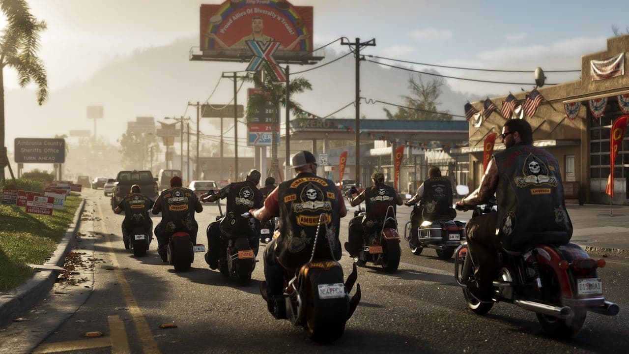 A column of motorcycles riding into Ambrosia past a county sheriff's office sign, a filling station and bunting-hung storefronts ahead.