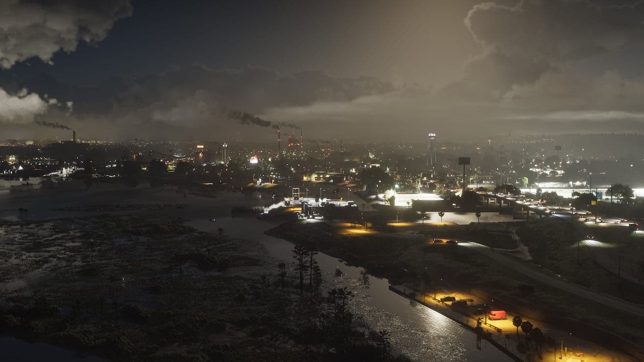 Ambrosia at night from the air, chimney stacks smoking over a lit industrial town with a river and highway running through it.