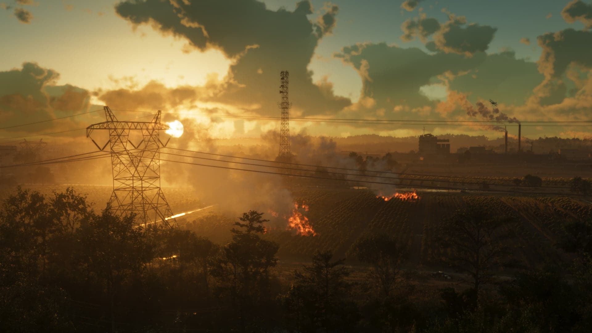 Crop fields burning at sunset in Ambrosia, smoke drifting across the rows beneath power lines, with a plant and its chimneys on the far ridge.