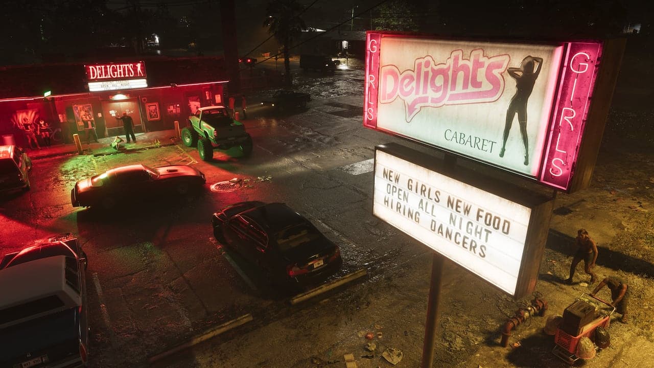 The lit sign of the Delights Cabaret on a wet Port Gellhorn street at night, cars parked outside the club under a dark sky.