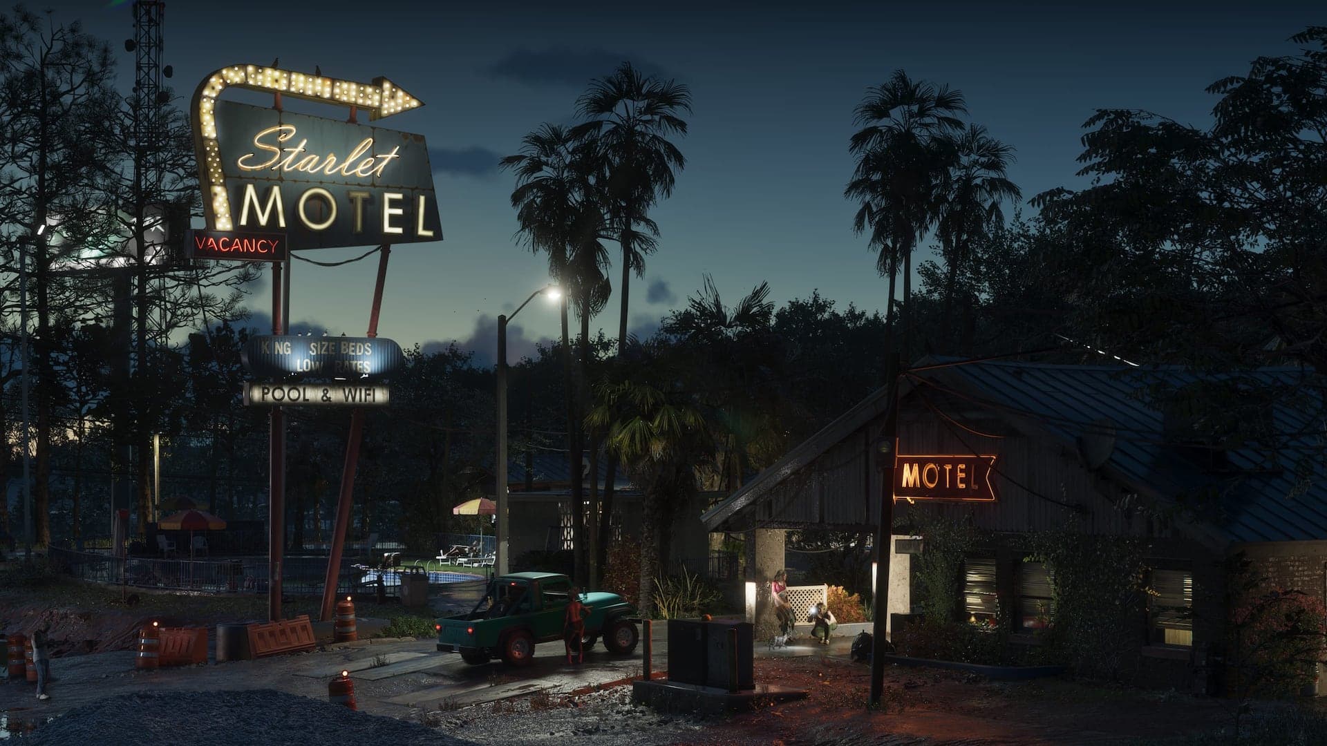 The neon sign of the Starlet Motel in Port Gellhorn at dusk, palm trees and a pickup truck beyond it.