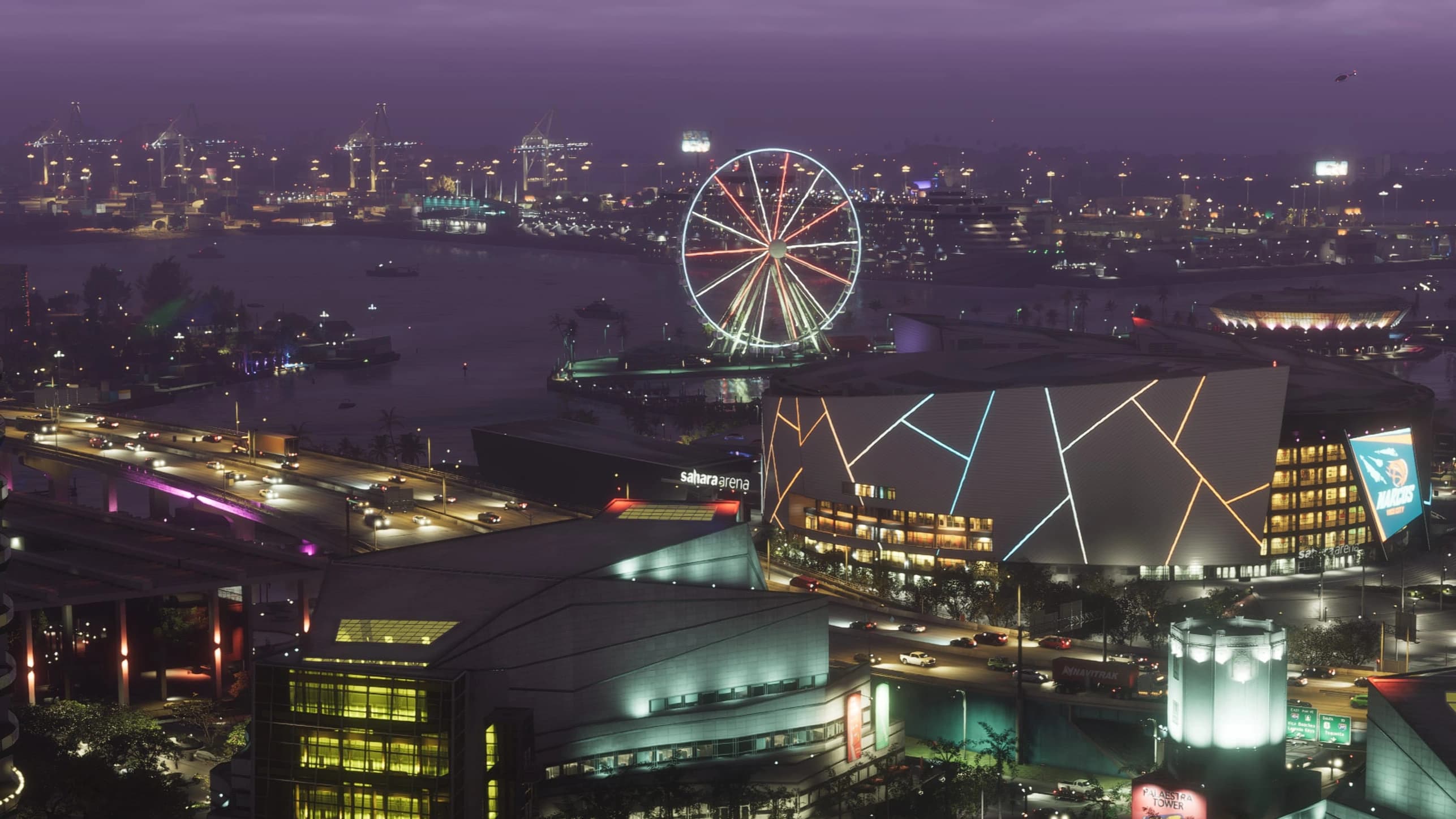 The Vice City waterfront at dusk: an illuminated ferris wheel and arena on the harbour front, with port cranes and shipping across the water.