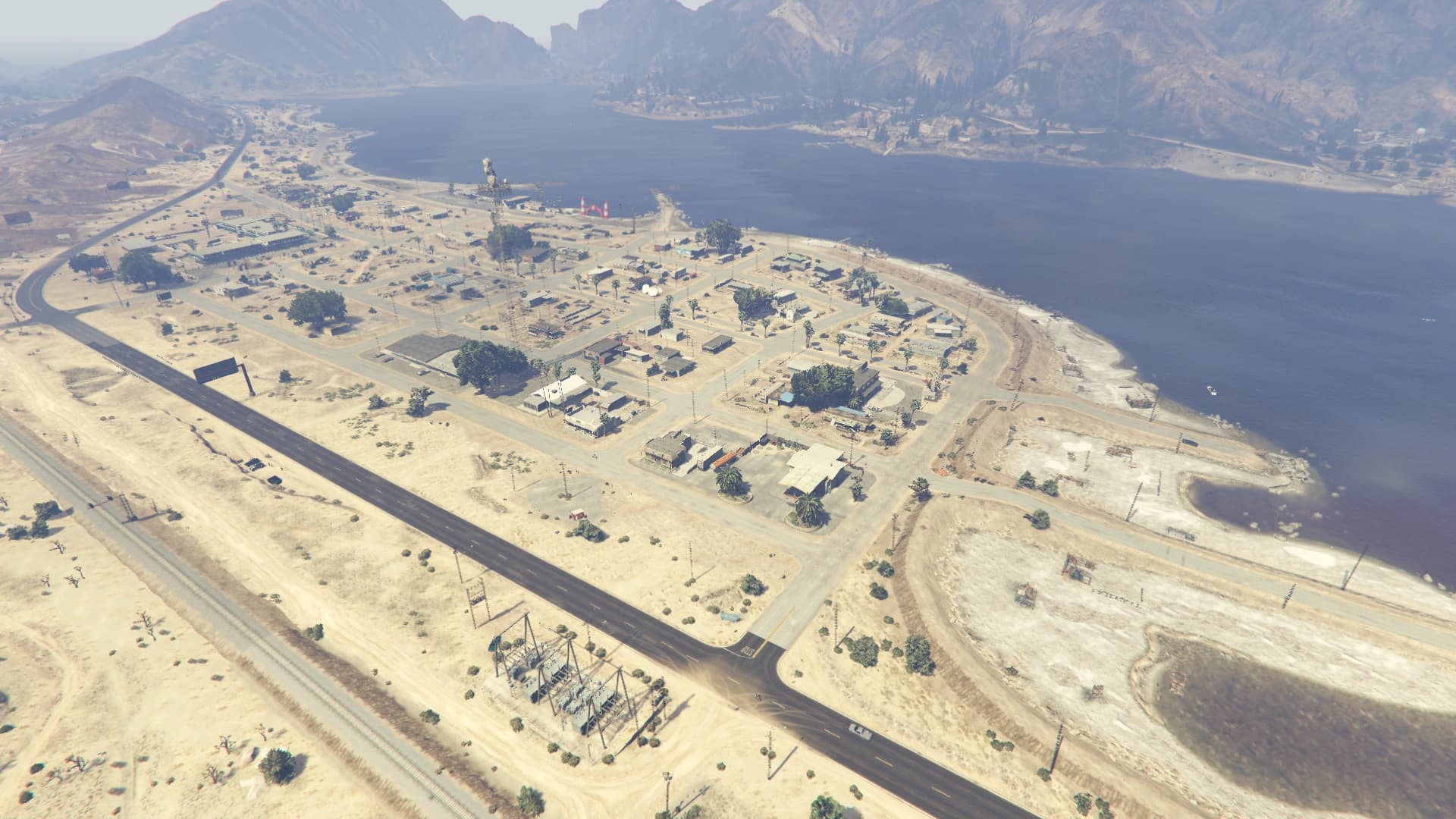 Blaine County from the air: the town of Sandy Shores spread along the shore of the Alamo Sea, with desert scrub and bare mountains beyond.