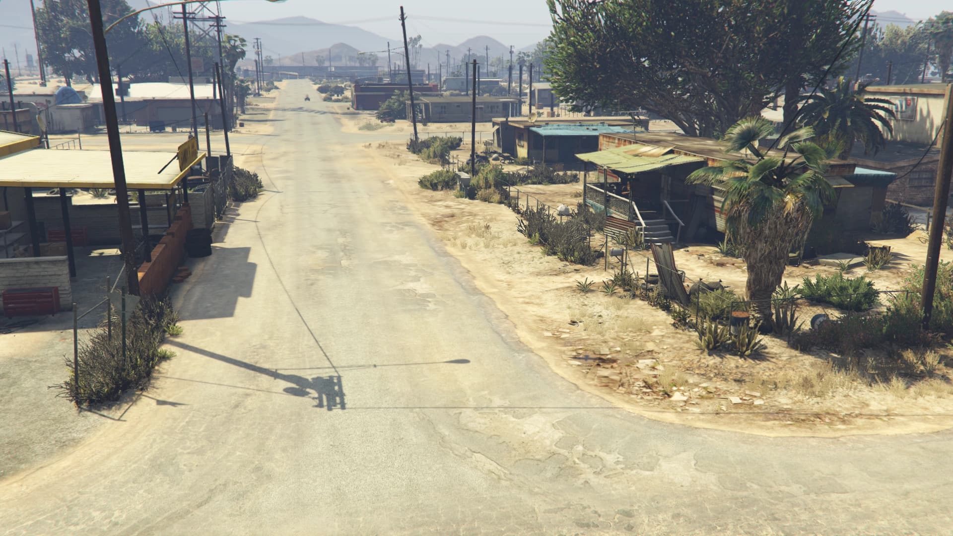 The main road through Sandy Shores, dust and low buildings on either side with the mountains beyond.