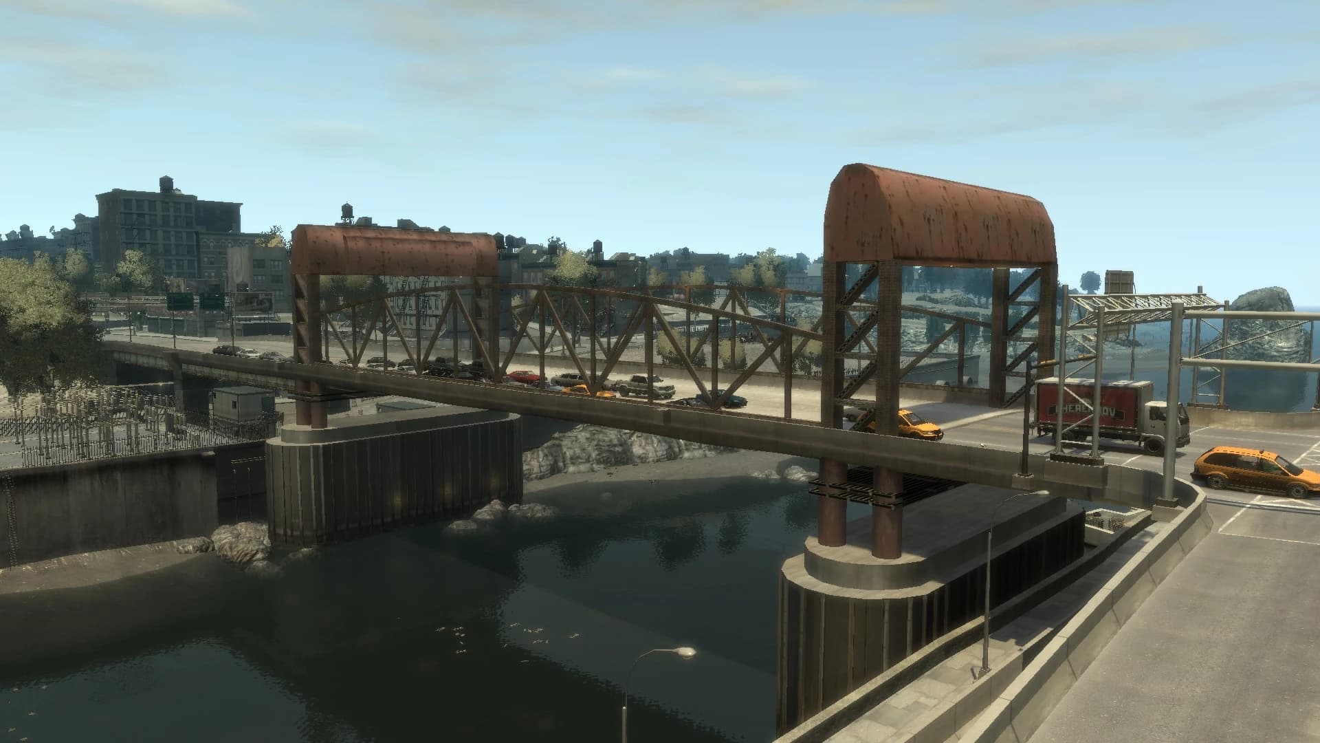 The Hickey Bridge crossing into Alderney, its rusted trusses above the water with Alderney’s blocks and waterfront beyond.