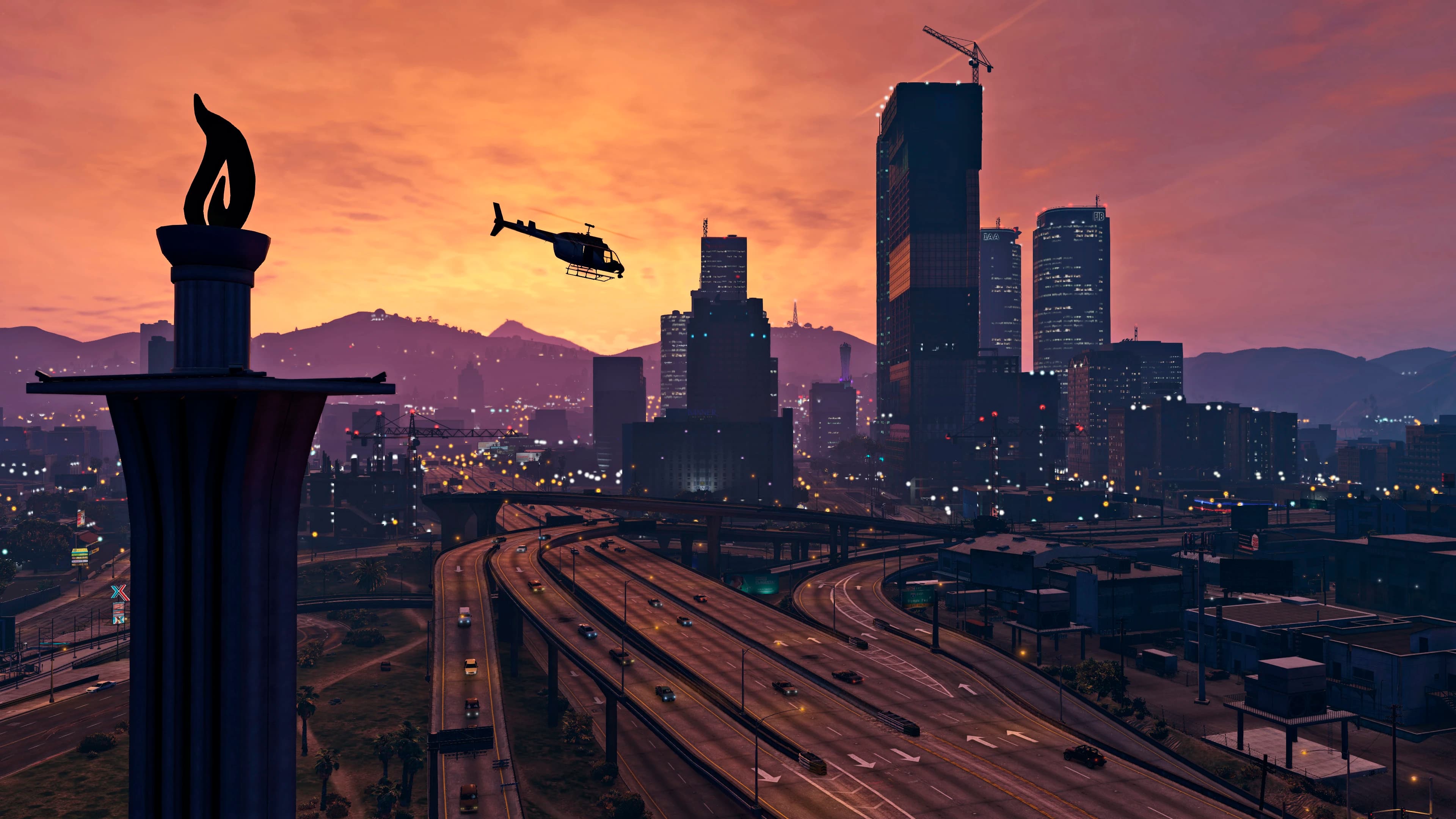 Downtown Los Santos at sunset, glass towers above the freeway with the hills behind them.
