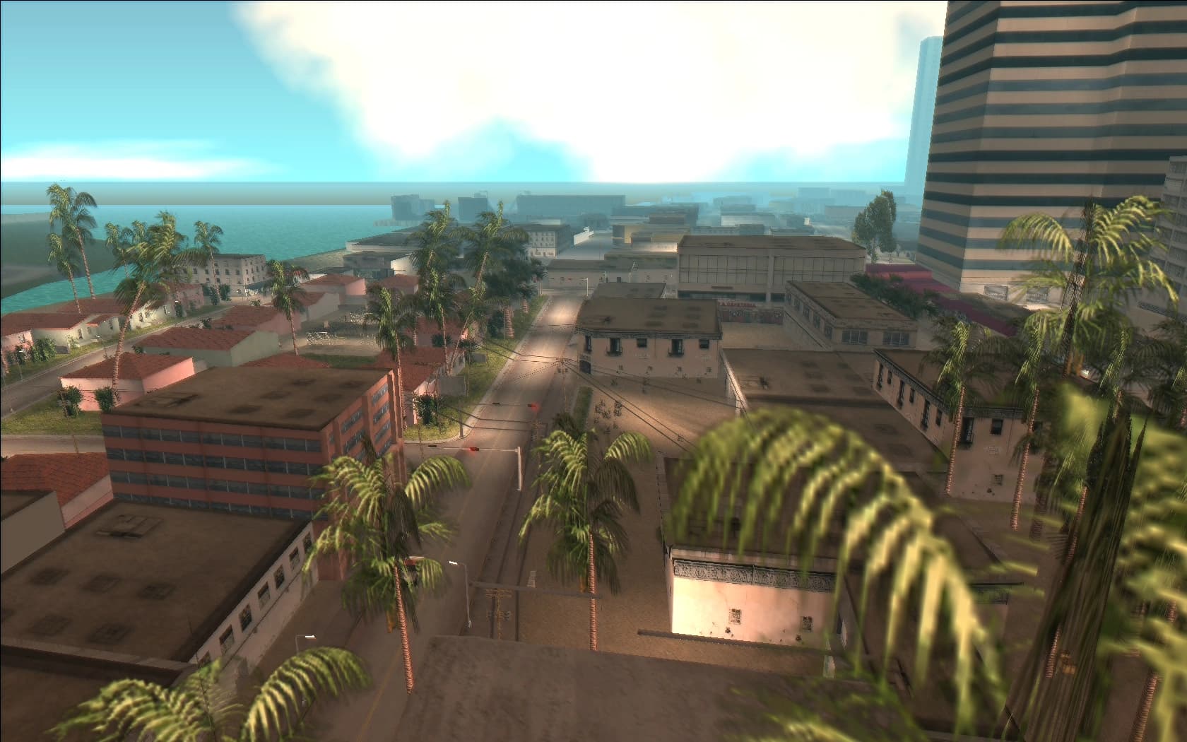 Little Havana's rooftops and streets under a bright sky, palms lining the road down to the water.