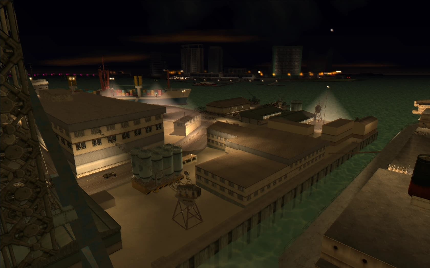 Viceport at night, warehouses and container yards along the water under crane lights.