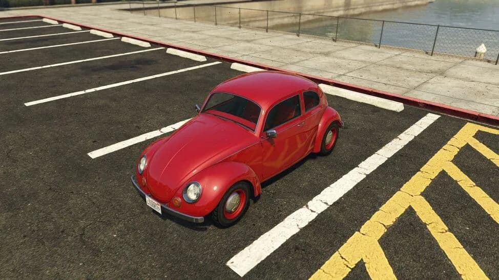 The BF Weevil, a red classic rounded two-door compact car, parked in a car park by the water, in GTA Online.