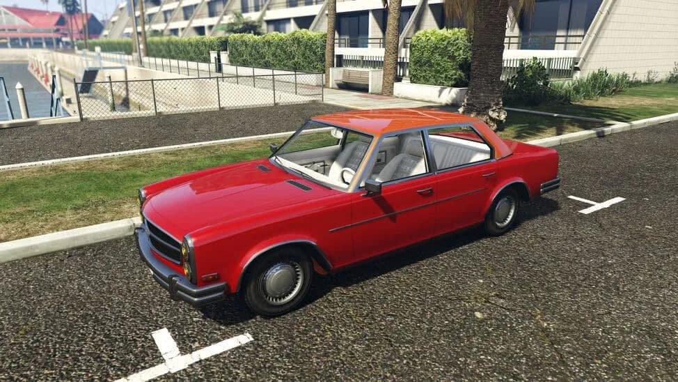 The Benefactor Glendale Custom, a red 1970s four-door saloon, parked beside a lawn, in GTA Online.