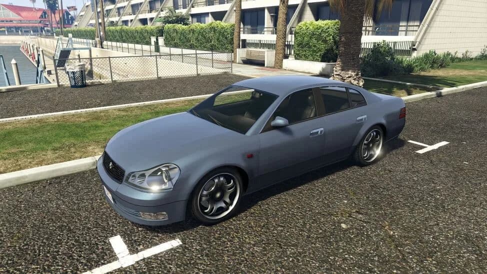 The Karin Intruder, a grey four-door saloon, parked beside a lawn, in GTA Online.