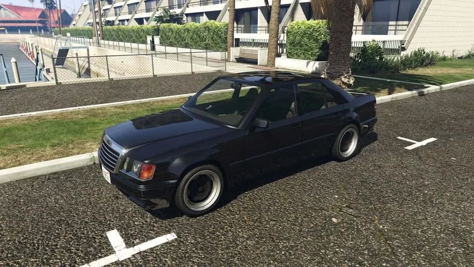 The Benefactor Vorschlaghammer, a black 1990s four-door performance saloon, parked beside a lawn, in GTA Online.
