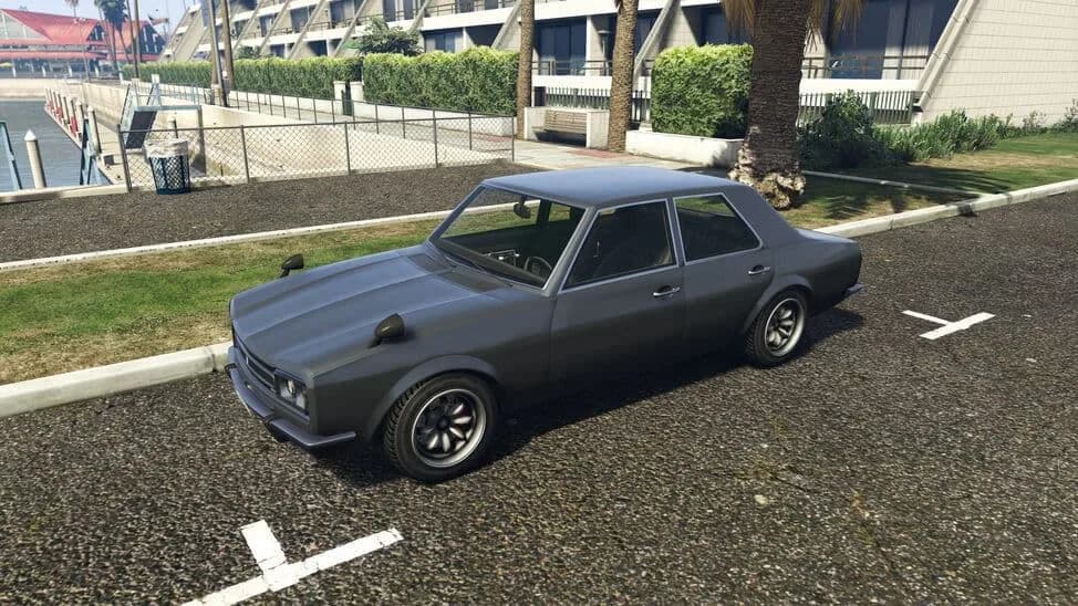 The Vulcar Warrener, a grey 1970s four-door saloon with wing mirrors on the fenders, parked beside a lawn, in GTA Online.