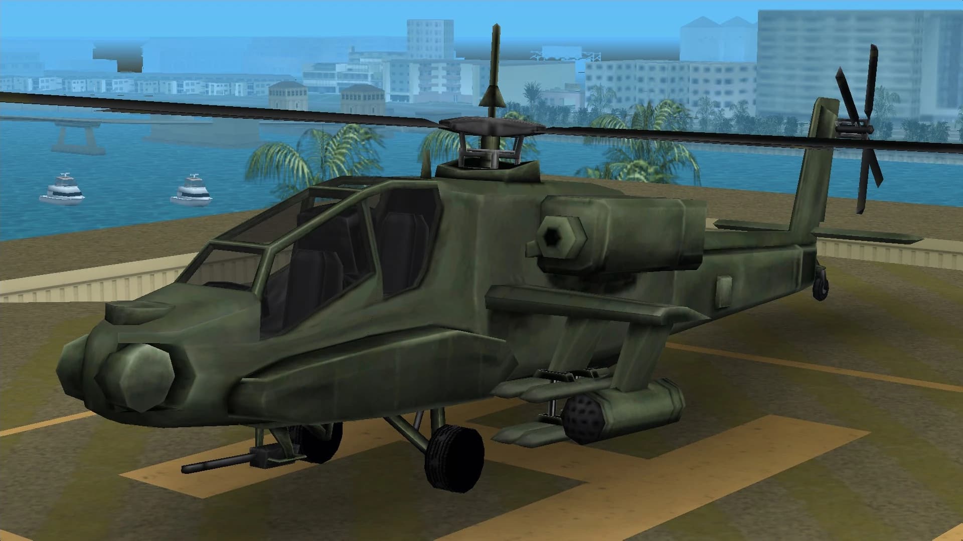 A green Hunter attack helicopter with rocket pods and a chin gun, on a helipad.