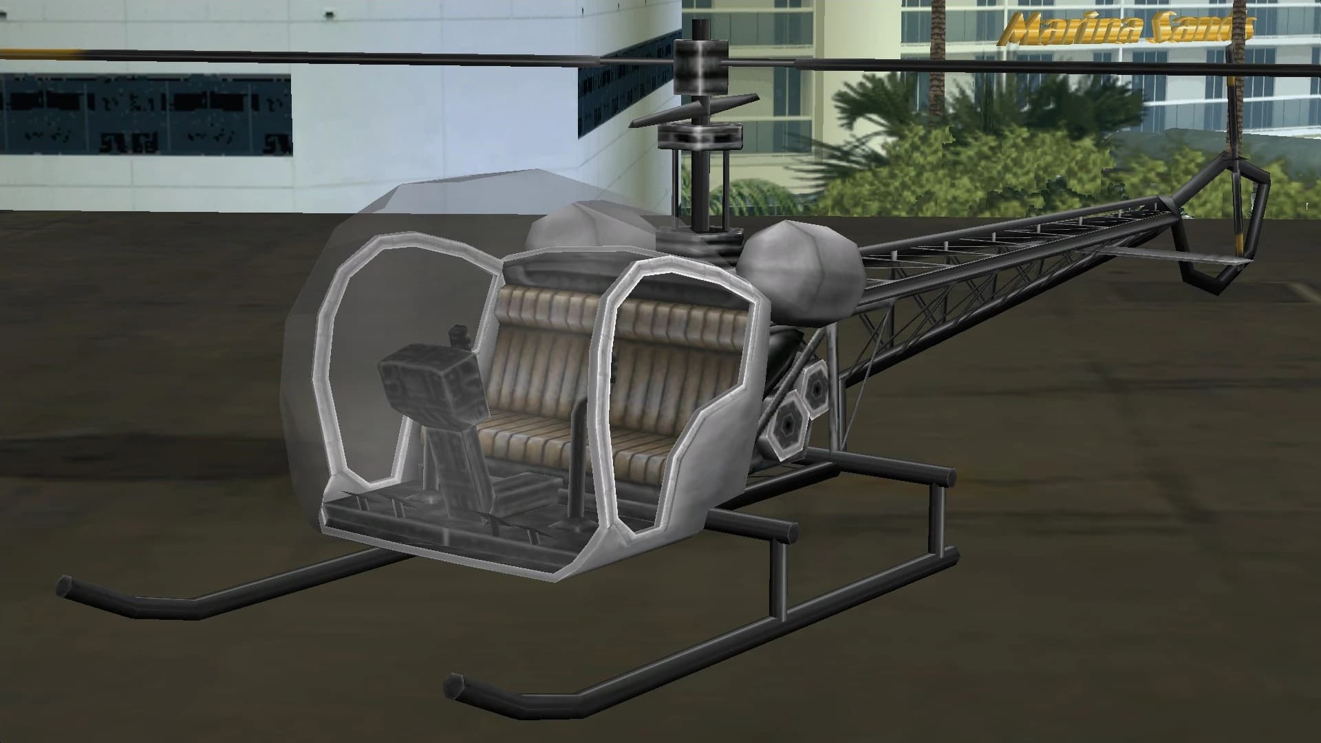 A grey Sparrow light helicopter on landing skids, on a helipad.