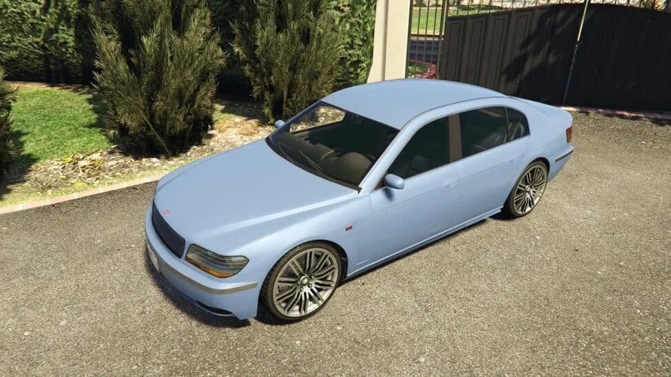 The Übermacht Oracle XS, a light blue luxury saloon, parked by a driveway, in GTA Online.