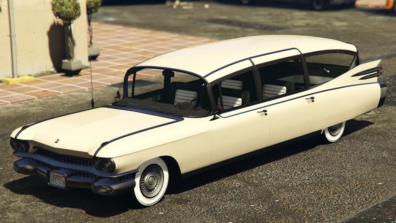 A cream Albany Brigham, a long finned 1950s sedan on whitewall tyres, front view.