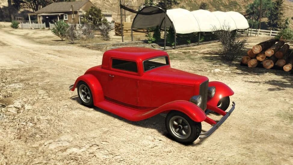 The Vapid Hustler, a red 1930s hot rod coupe, parked on a dirt yard, in GTA Online.