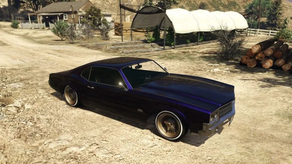 The Declasse Sabre Turbo Custom, a dark purple lowered 1970s muscle coupe on gold wire wheels, parked on a dirt yard, in GTA Online.