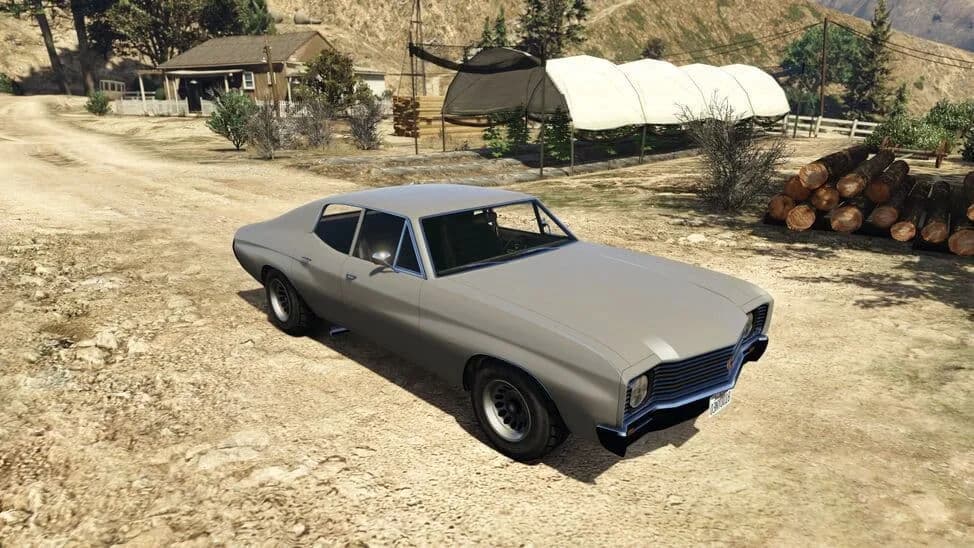 The Declasse Tulip, a grey early-1970s muscle coupe, parked on a dirt yard, in GTA Online.