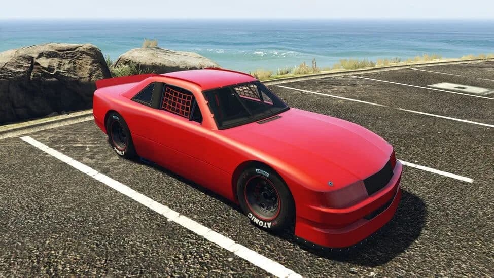 The Declasse Hotring Sabre, a red stock car with a roll cage, parked by the coast, in GTA Online.
