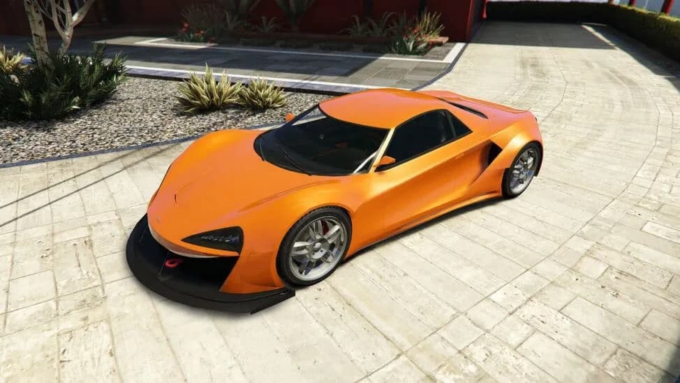 The Progen Itali GTB Custom, an orange mid-engined supercar with a front splitter, parked on a paved courtyard, in GTA Online.