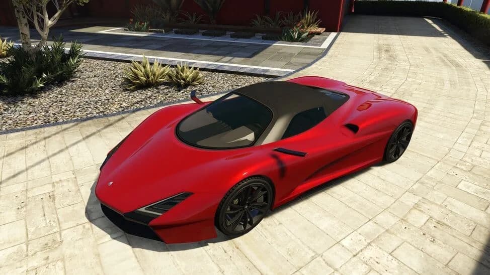 The Överflöd Zeno, a red hypercar with a black roof, parked on a paved courtyard, in GTA Online.