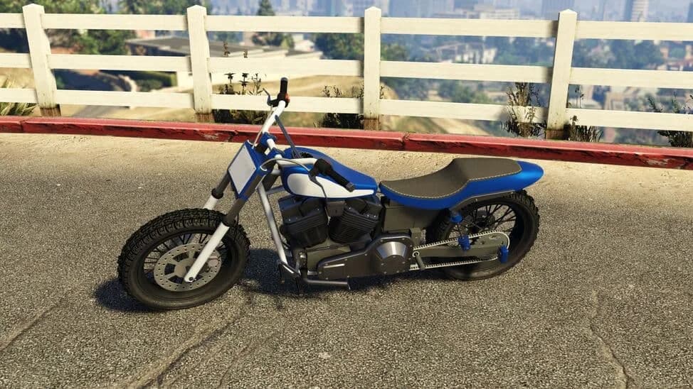 The Western Cliffhanger, a blue and white flat-track style motorcycle, parked by a white fence, in GTA Online.