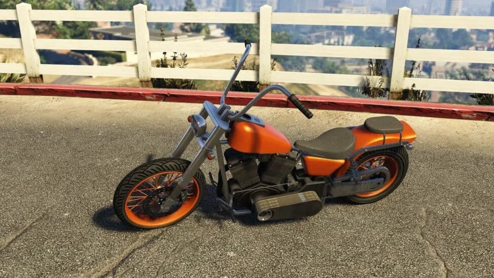 The Western Daemon Custom, an orange chopper motorcycle with high bars, parked by a white fence, in GTA Online.