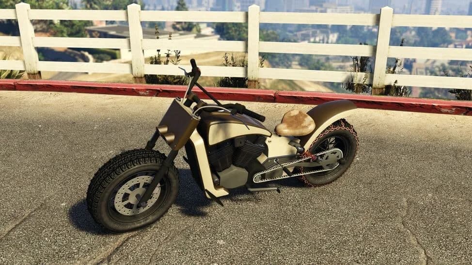 The Western Gargoyle, a cream bobber motorcycle with knobbly tyres, parked by a white fence, in GTA Online.