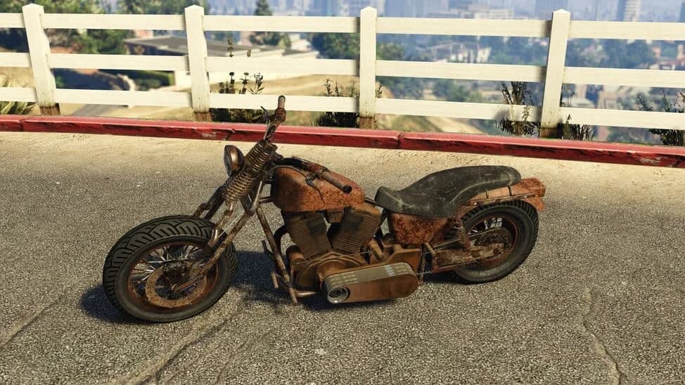 The Western Rat Bike, a rusted chopper motorcycle, parked by a white fence, in GTA Online.