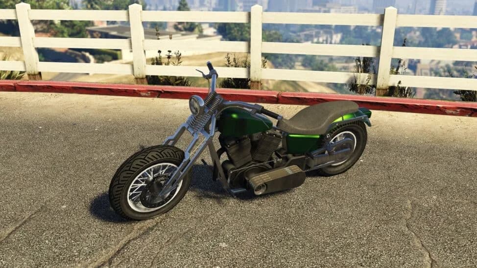 The Western Wolfsbane, a black and green bobber motorcycle, parked by a white fence, in GTA Online.
