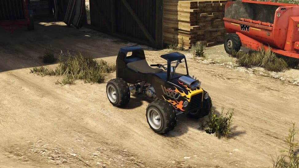 The Nagasaki Hot Rod Blazer, a black quad bike with flame paint and an exposed engine, parked by a barn, in GTA Online.