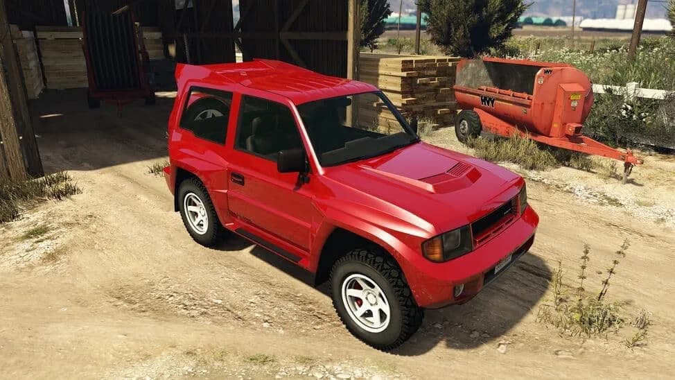 The Maibatsu MonstroCiti, a red three-door compact off-roader, parked by a barn, in GTA Online.