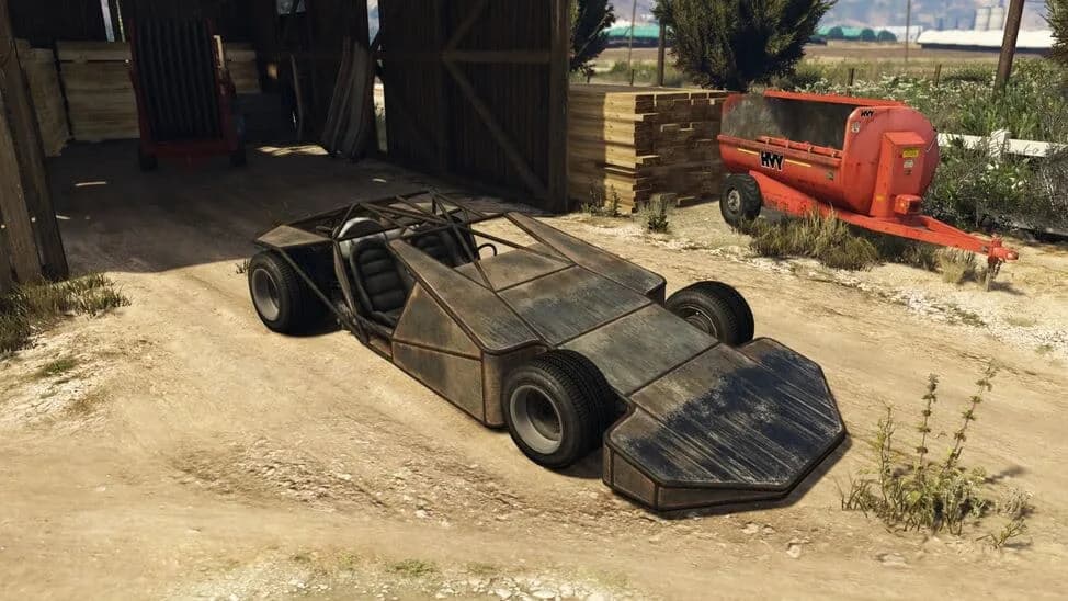 The Ramp Buggy, a dark open buggy with a wide wedge ramp at its front, parked by a barn, in GTA Online.