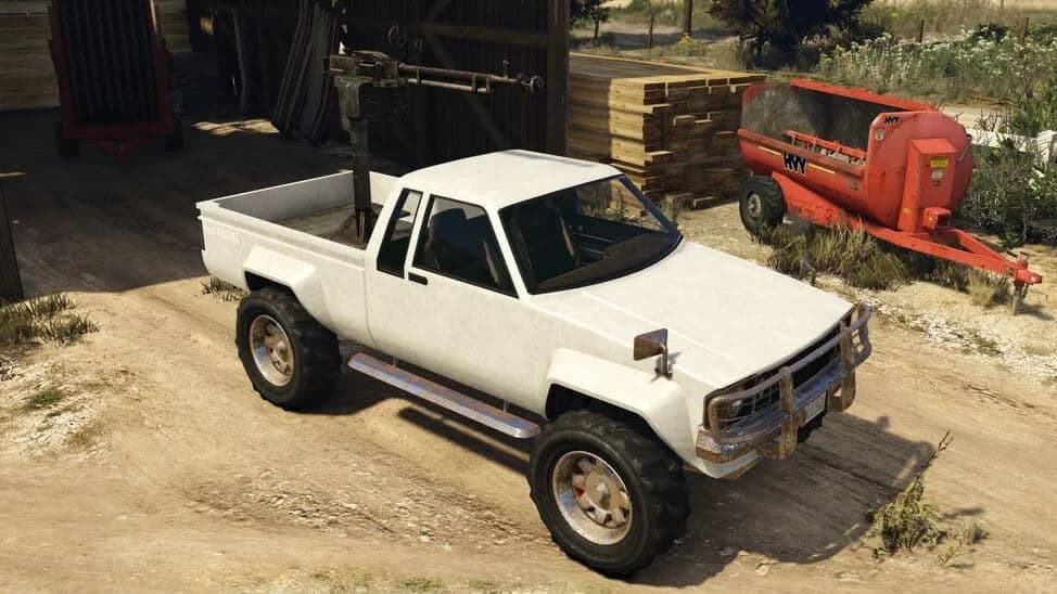 The Karin Technical Custom, a clean white pickup with a machine gun mounted in its bed, parked by a barn, in GTA Online.