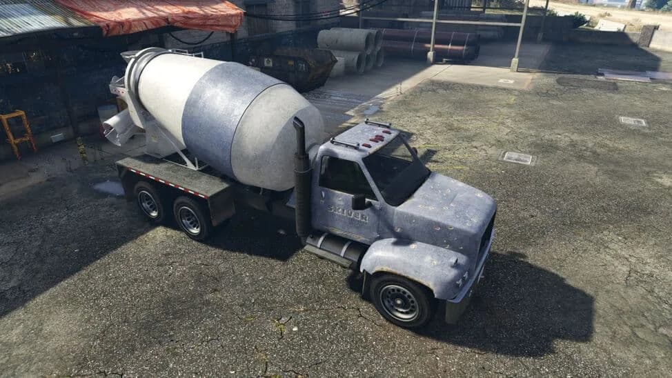 The HVY Mixer, a weathered blue-grey cement mixer truck, parked in a builder's yard, in GTA Online.