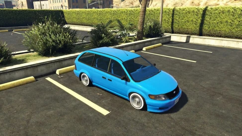 The Vapid Minivan Custom, a blue lowered minivan on whitewall wire wheels, parked in a car park, in GTA Online.