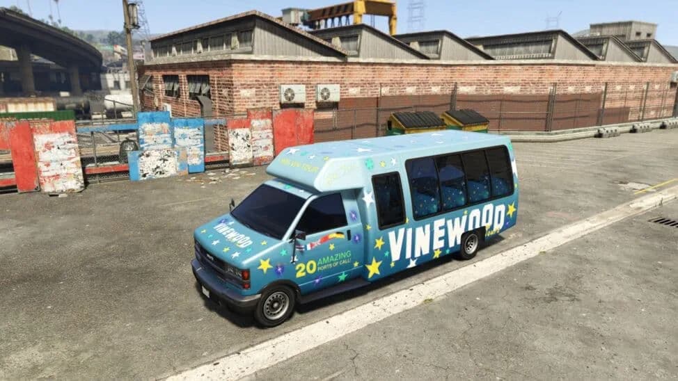 The Tour Bus, a blue minibus in a sightseeing-tour livery, parked by a brick warehouse, in GTA Online.