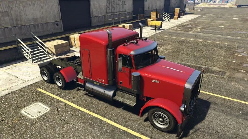 The JoBuilt Phantom, a red long-nose semi tractor unit, parked by a warehouse, in GTA Online.