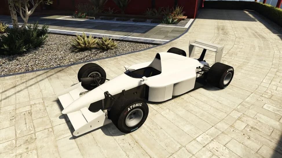 The Progen PR4, a white open-wheel formula racing car, parked on a paved courtyard, in GTA Online.