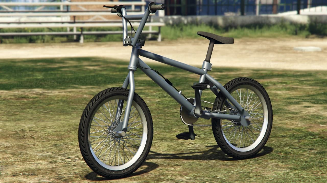 A grey BMX bicycle standing on grass, front three-quarter view.