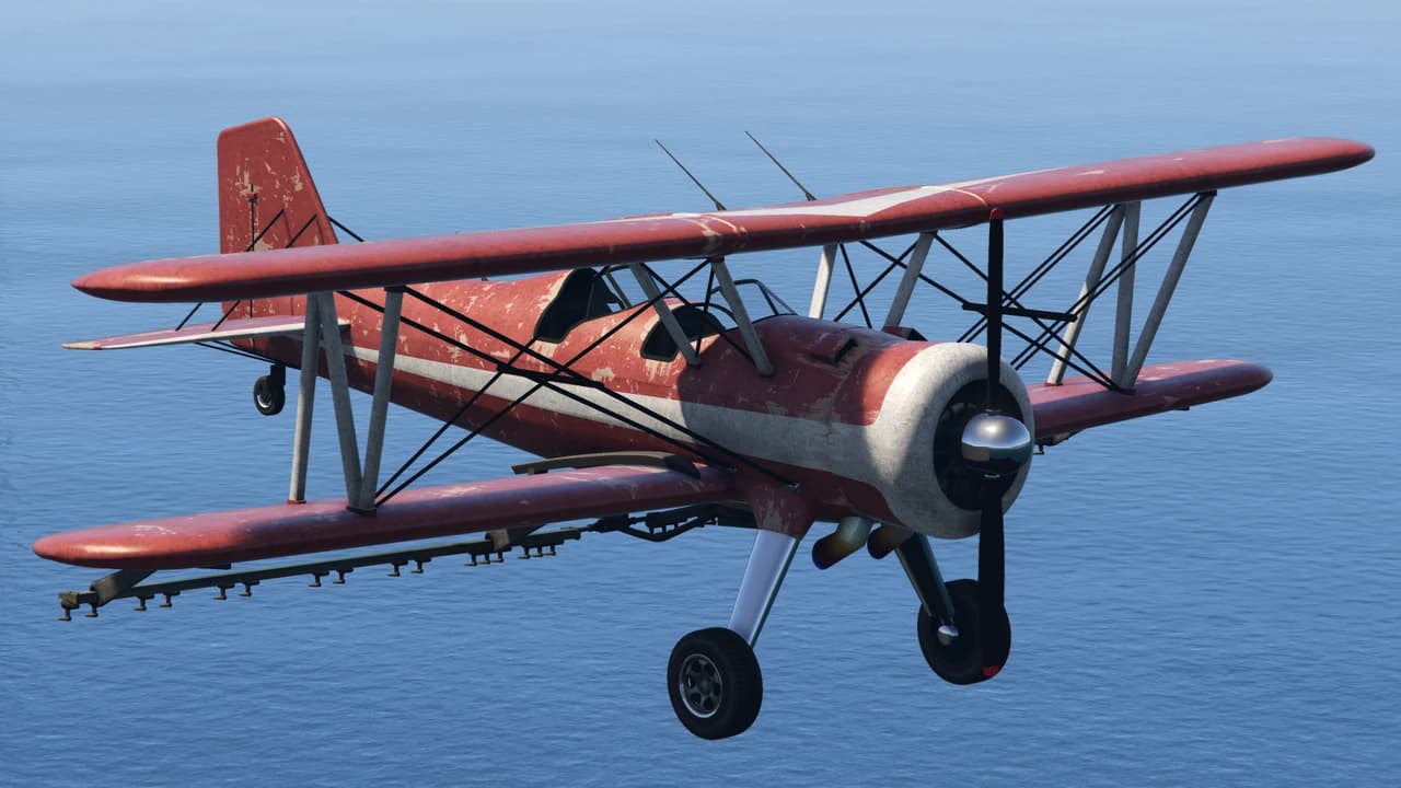 A weathered red and white Duster crop-dusting biplane in flight, with spray booms under the lower wing.